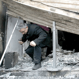 What's left of a Greek bank. A man exits a burned bank in the center of Athens. The firemen are putting out the smoldering buildings and the cleanup crews are sweeping the rubble after a night of rioting in the center of Athens, after the members of the Parliament have approved new harsh austerity measures requested by the country's private creditors to prevent the beleaguered country from defaulting.